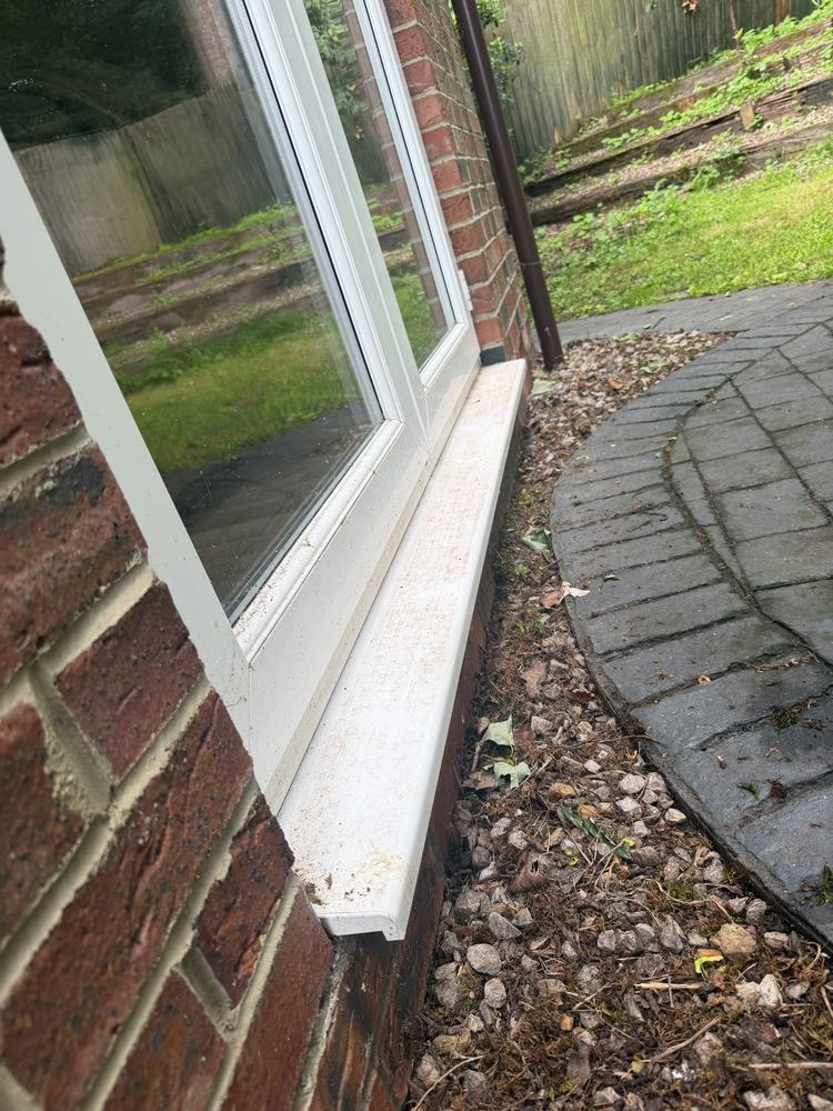 A window and sill before cleaning, with visible dirt on the glass and frame.