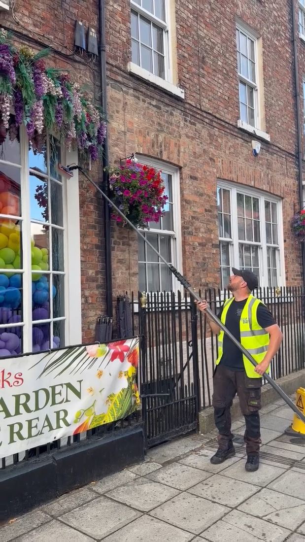 A Clear As Day operative in a hi-vis vest cleaning the frontage of Dr. Inks with a water fed pole.