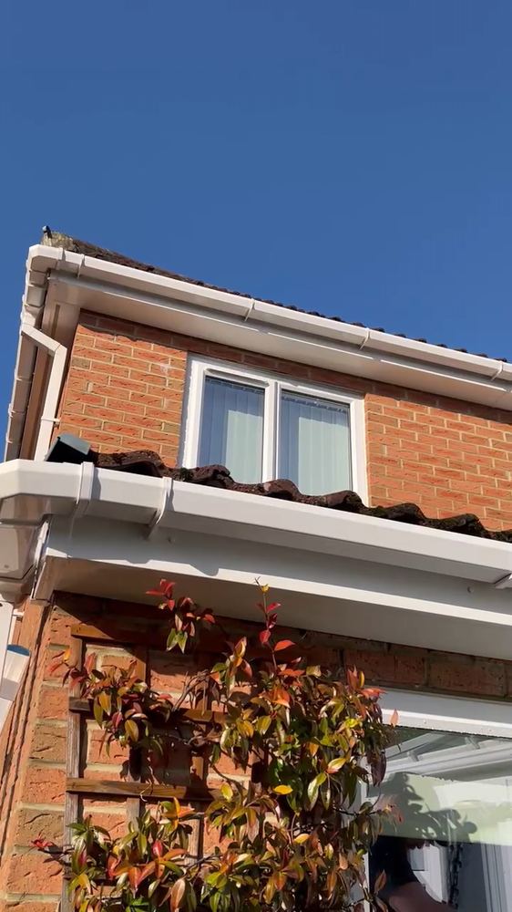 A clean white fascia and soffit run against a blue sky after cleaning.