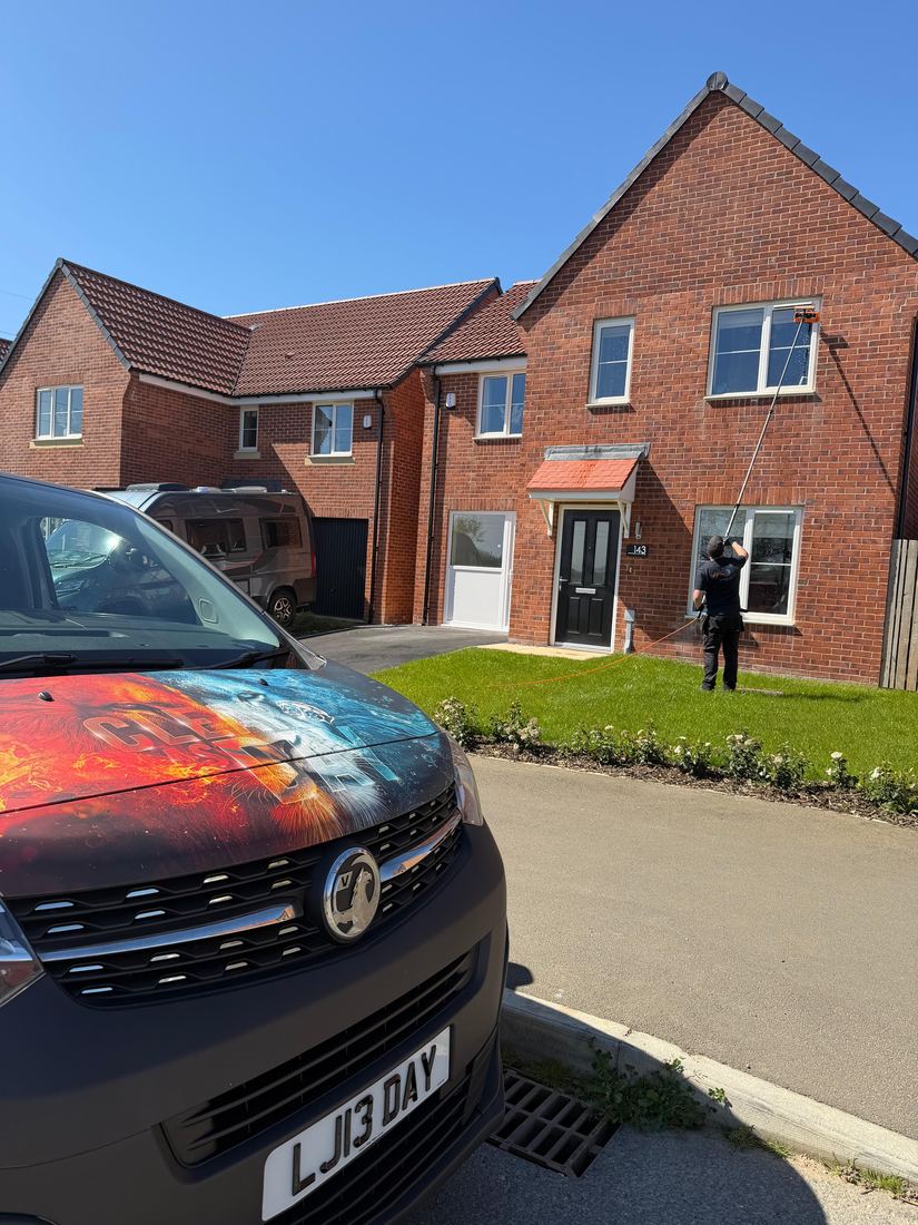 The Clear As Day van on a driveway while a new-build estate house has its windows cleaned.