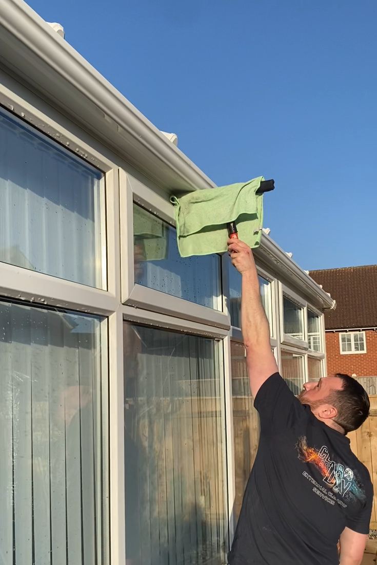 Liam wiping down conservatory glass by hand at the end of a job.