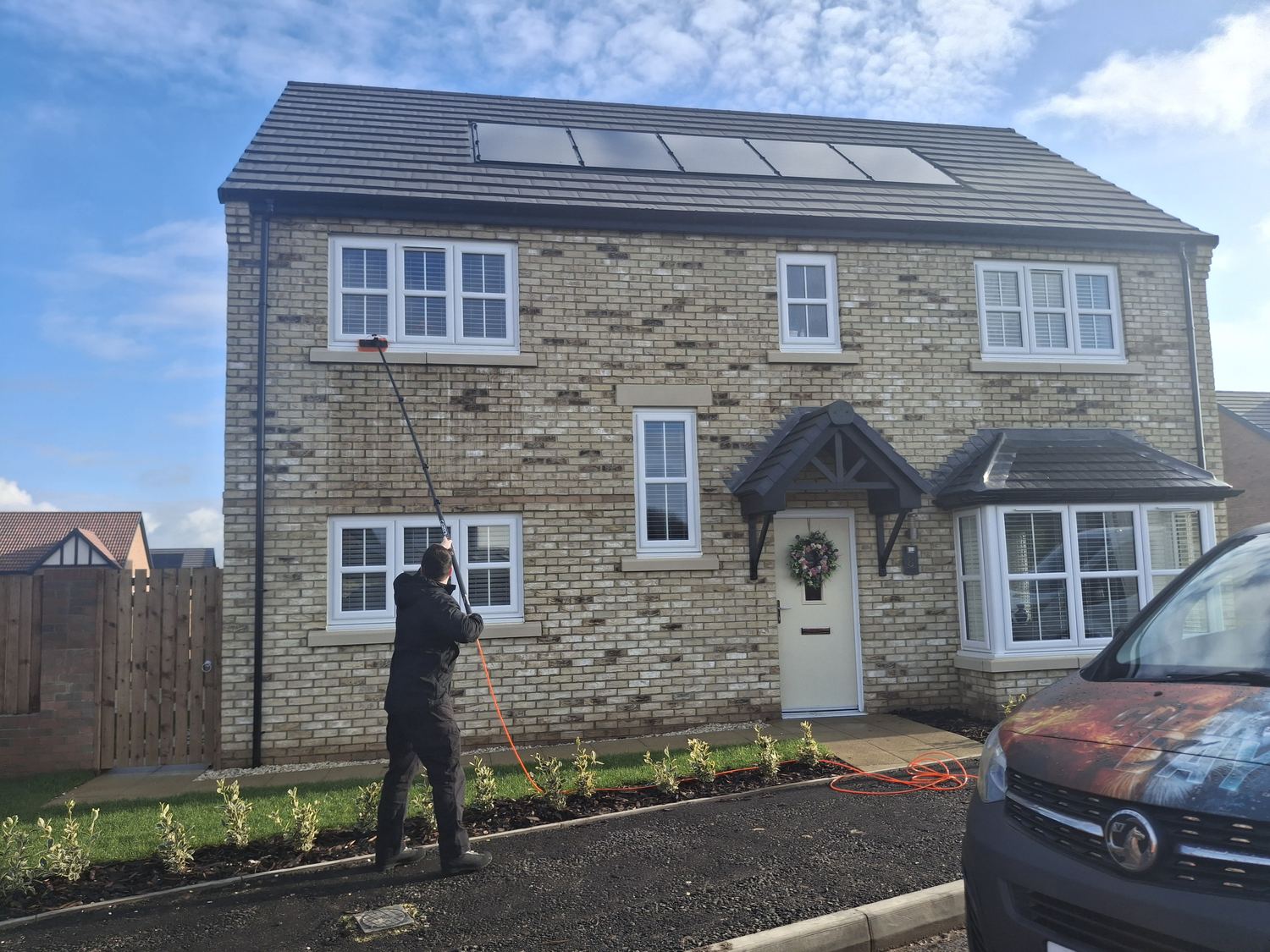 Clear As Day cleaning the upstairs windows of a stone-fronted house with a water fed pole.