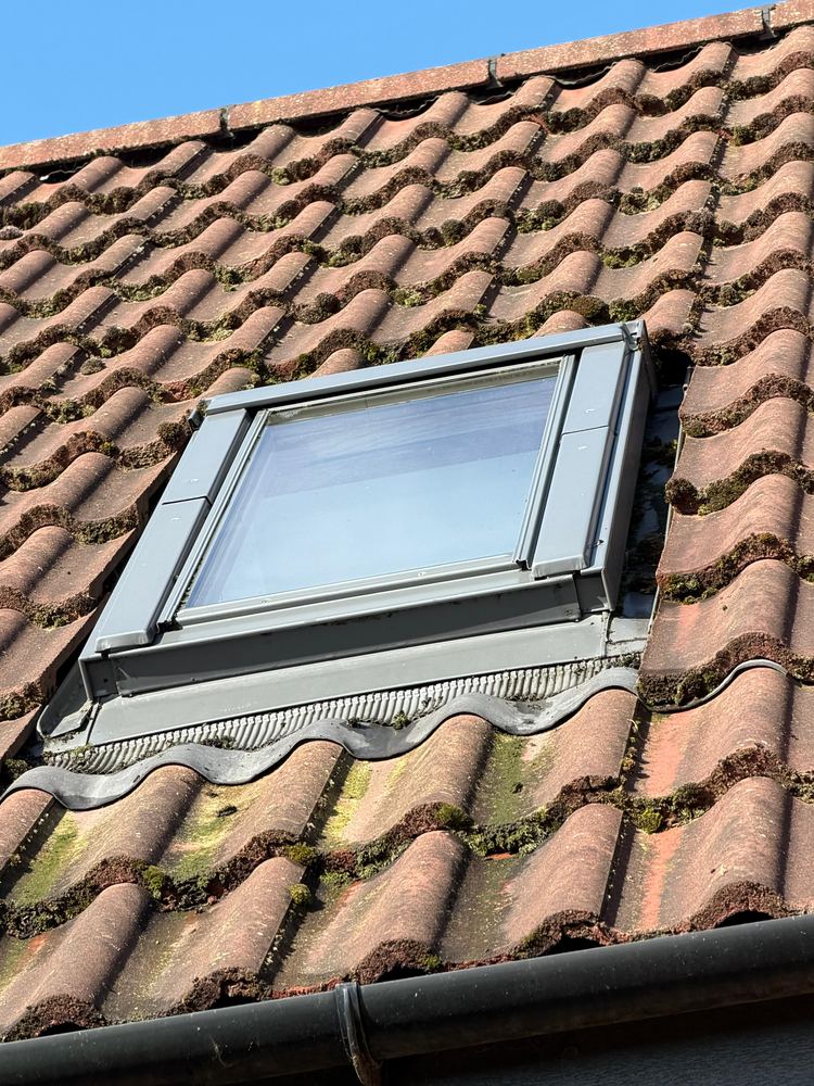 A cleaned Velux roof window set into a tiled roof.